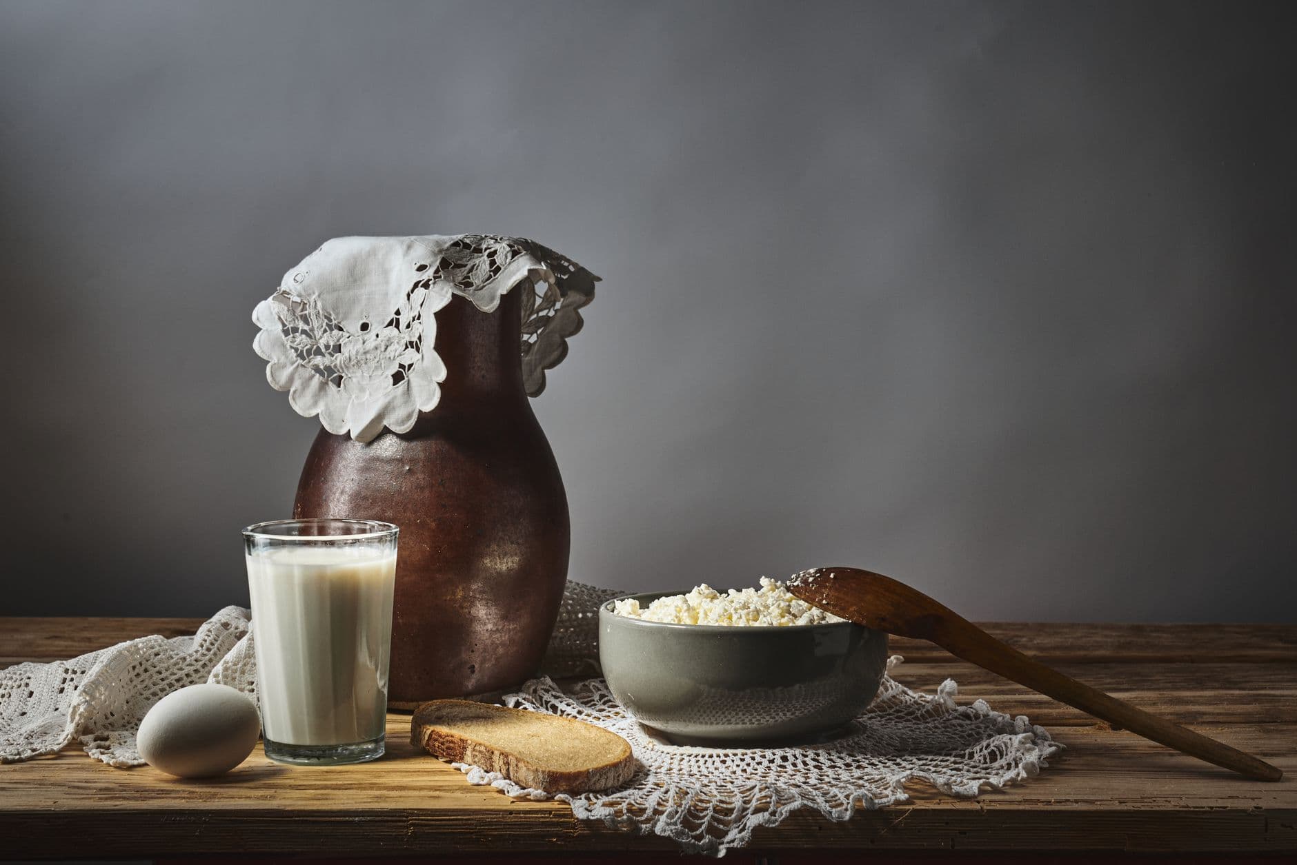 garrafa de leite, queijo cottage e pão sobre uma mesa de madeira