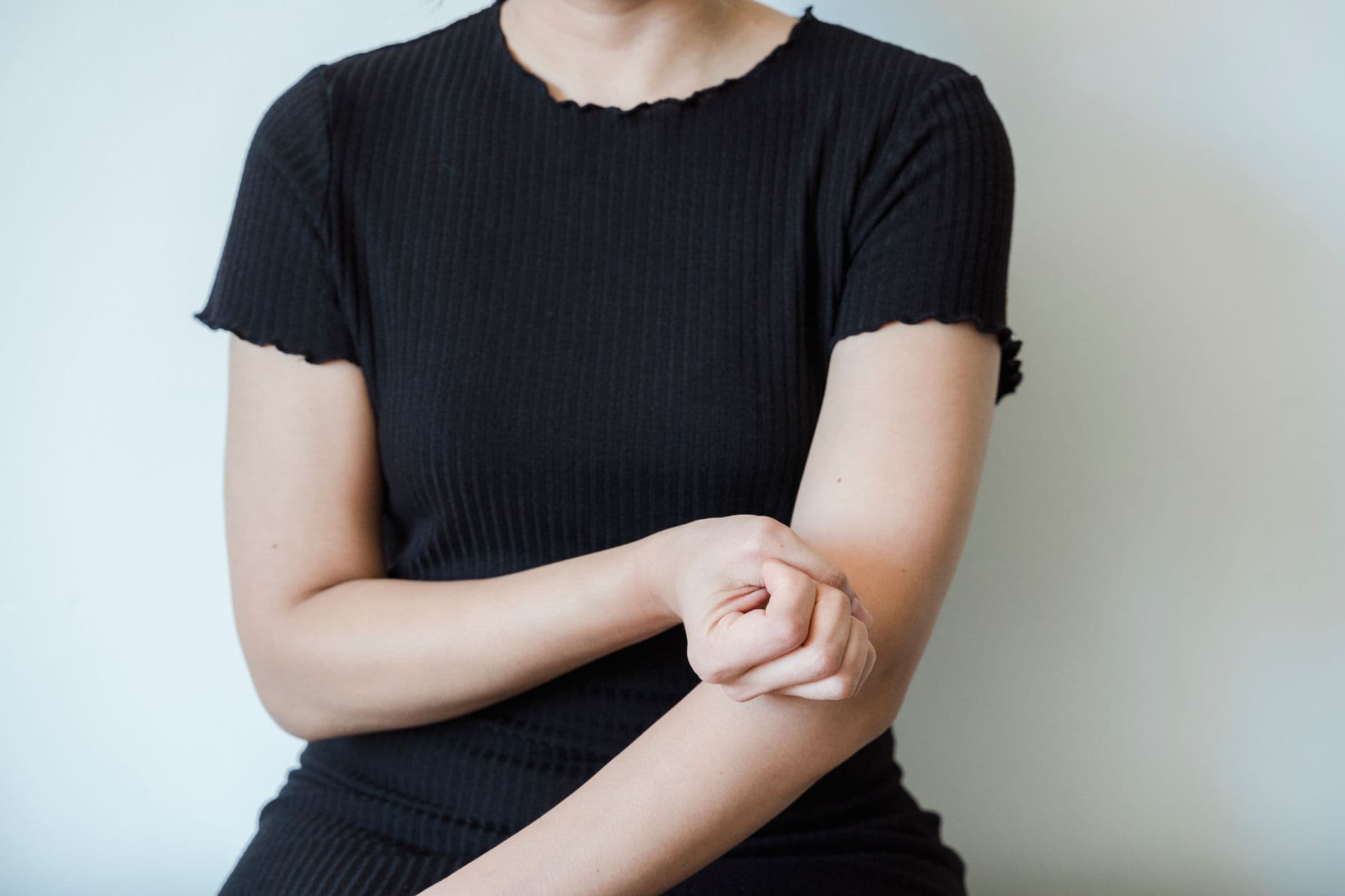 mulher de camiseta preta segurando o antebraço perto do cotovelo