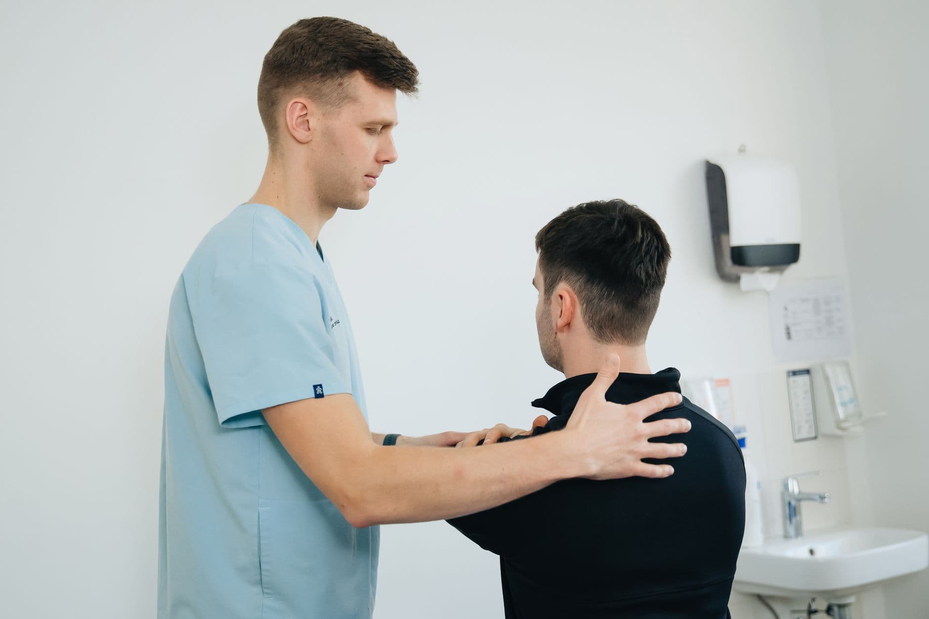 fisioterapeuta atendendo o ombro de um paciente em consultório