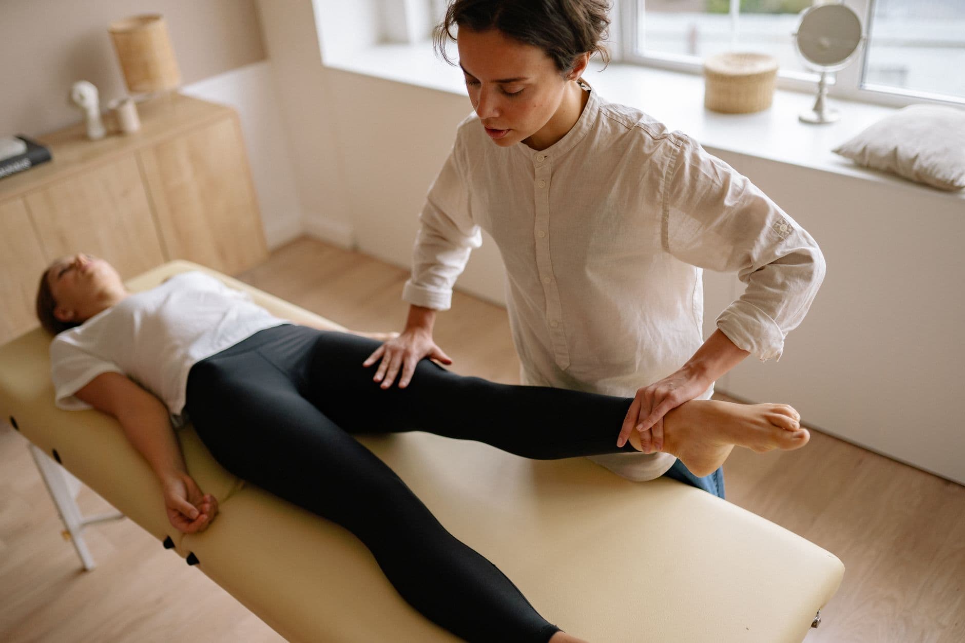 fisioterapeuta acompanhando exercício de perna em sala de atendimento